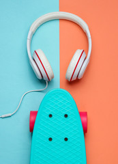 Hipster outfit. Skateboard with headphones on colored pastel background. Creative fashion minimalism. Trendy old fashionable style. Minimal summer fun. Music concept