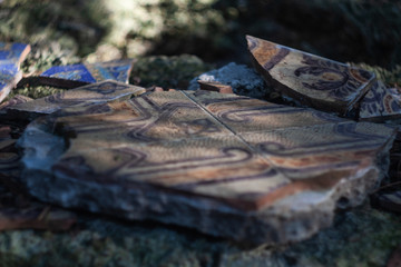 Abandoned artistic hand made tiles on a mossy sone