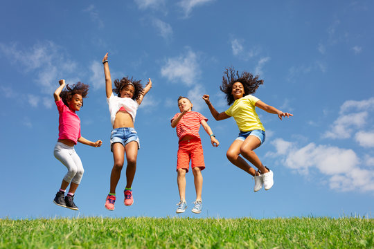 Group of children jump over blue sky and clouds