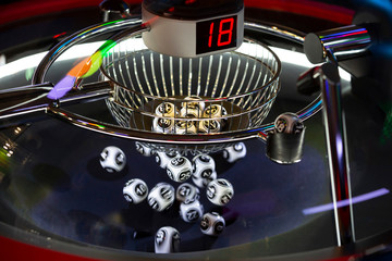 Black and white lottery balls in a rotating bingo machine. Number 18