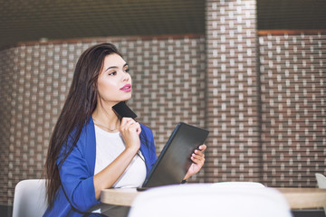 Beautiful young adult girl pays online using tablet and credit card