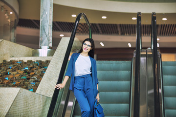 Young adult beautiful brunette girl happy businesswoman on escalator in business center