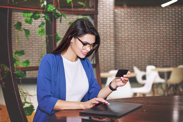 Beautiful young adult girl pays online using tablet and credit card