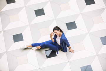 Young adult beautiful brunette girl happy on tile with geometric pattern top view