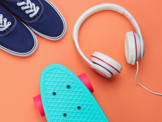 Hipster fashion look. Skate, sneakers, headphones on orange background. Top view. Flat lay