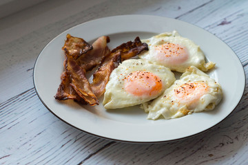 Fried eggs and bacon on a white plate
