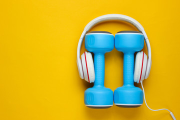 Sports equipment on yellow background. Sport lifestyle. Dumbbells, headphones. Fitness concept. Top view, minimalism, flat lay