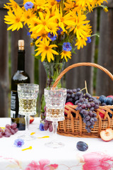 bouquet of flowers, wine, glasses and grapes against the background of an old fence