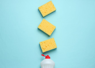 Set of housewives for washing dishes. Dishwasher. Bottle of washing utensils, sponges on blue pastel background. Top view.