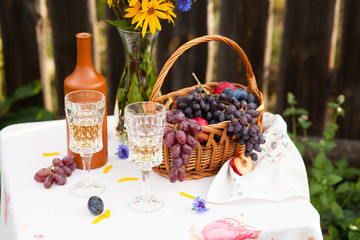 bouquet of flowers, wine, glasses and grapes against the background of an old fence