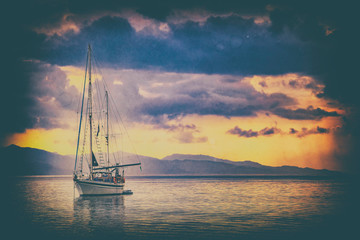 Old photo in vintage style as a Natural background. There is a Yacht in the Mediterranean sea at sunrise, Cagliari, Italy. he sun illuminates the island with beautiful golden colors.