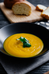 Pumpkin soup served in a bowl with bread and parsley