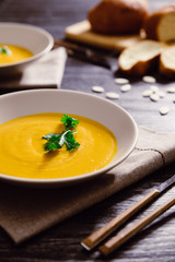 Pumpkin soup served in a bowl with bread and parsley