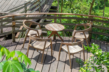 Wooden table and chairs in empty tropical cafe next to rice terraces in island Bali, Indonesia