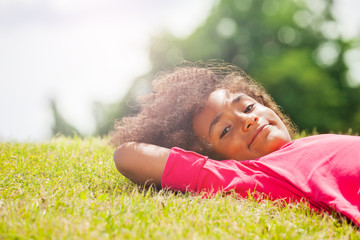 Portrait of a little girl rest on the park lawn