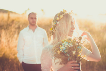 Back view on bride and groom holding hands in sunny summer day. Outdoor wedding and relationsheep...