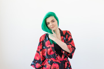 Fashion, style, hair coloring and people concept - young woman with green hair in colourful kimono over the white background