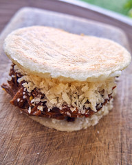 arepa stuffed with beef and cheddar cheese, top view with selective focus and shallow depth of field. On a wooden board