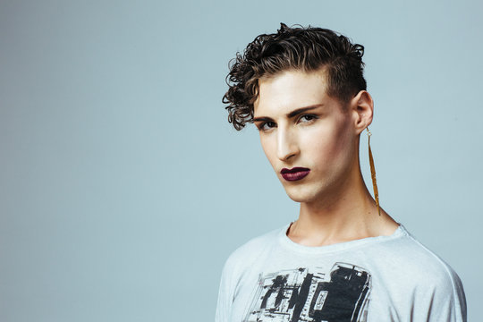 Portrait of a beautiful young  man with lipstick and earring