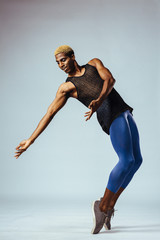 Portrait of a young man in studio dancing modern dance on toe tips