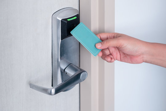 Hand using electronic smart contactless key card for unlock door in hotel or house.