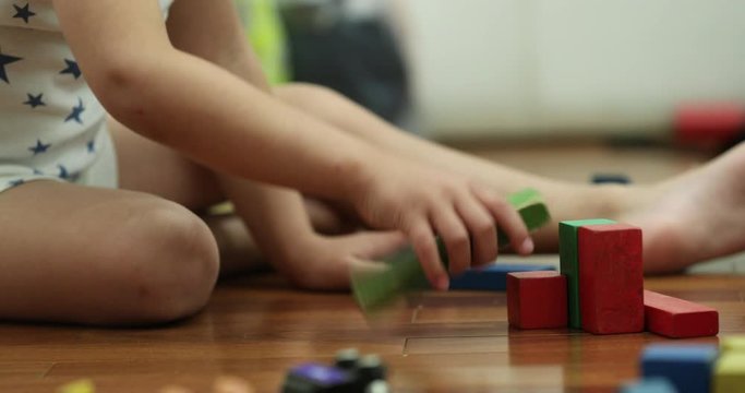 Toddler playing with toys in bedroom at night wearing pajamas contructing with wooden puzzle pieces