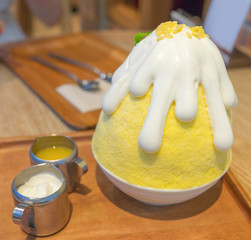 Mango kakigori (Bingsu) The Japanese ice shaved dessert served with sticky rice and mango sauce, topped with coconut cream. Famous dessert in Japan on summer.