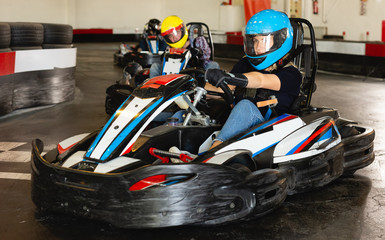 Female racer in helmet driving kart on track