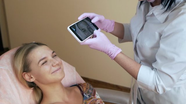 Beautician makes a photo of the face on the phone after the procedure