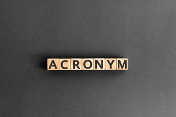acronym - word from wooden blocks with letters, use of acronyms in the modern world abbreviation concept, random letters around, top view on wooden background - obrazy, fototapety, plakaty