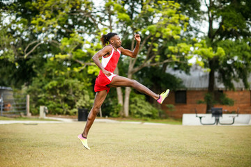 Fototapeta premium Young Handsome African American Black Male outside running in the field of a small town in georgia city ampitheater. track and field star