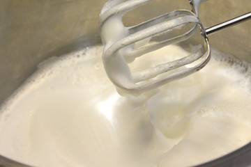 Whipped egg whites and sugar in stainless steel pot for baking cream topping