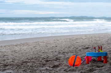 Obraz premium Toys on beach, blue sea, white sea foam, blue sky, blurred background.