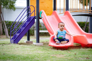 Nonthaburi, Thailand, Aug 28, 2019 - Little baby boy sitting on slider in public park