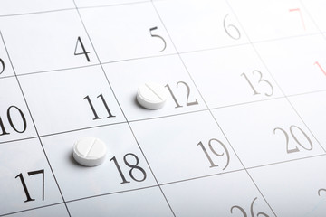 two pills on the calendar a month. white tablets round shape on a calendar sheet
