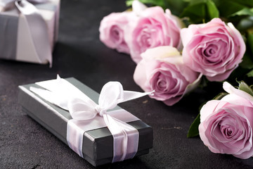 Pink roses and a gift box on a stone background. Vintage style, retro interior with flowers. Space for text
