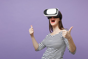 Young brunette woman girl in casual striped clothes posing isolated on violet purple background studio portrait. People sincere emotions lifestyle concept. Mock up copy space. Gesturing in vr headset.