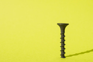 Black screw on a yellow background. Free space for an inscription.