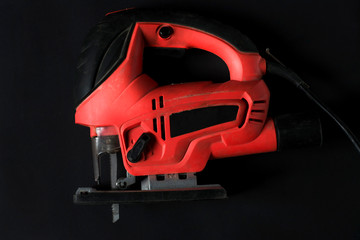 Naklejka premium Hand electric jigsaw on a black background.