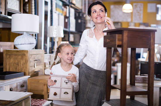 Woman with  daughter talking on the phone  in a furniture store