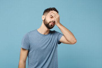 Young man in casual clothes posing isolated on blue wall background, studio portrait. People sincere emotions lifestyle concept. Mock up copy space. Putting hand on head face, keeping eyes closed.