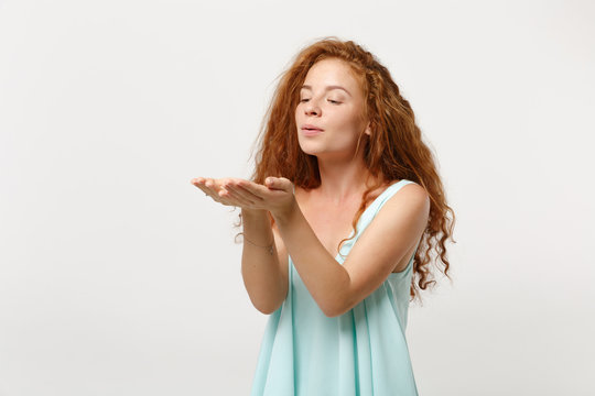 Young pretty smiling redhead woman girl in casual light clothes posing isolated on white background in studio. People sincere emotions lifestyle concept. Mock up copy space. Blowing sending air kiss.
