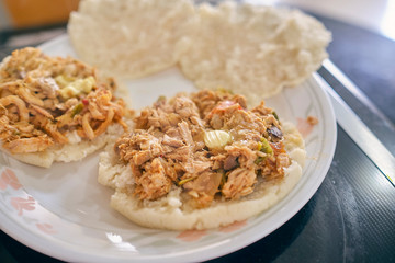 Arepas with shredded chicken, butter and cheese. Hot, you can see the steam and the butter melting. Served on a white plate.