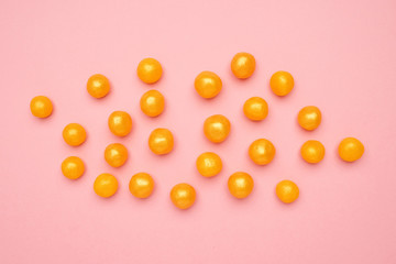 Fototapeta na wymiar Sweet yellow candies on a pink background, round sweet food