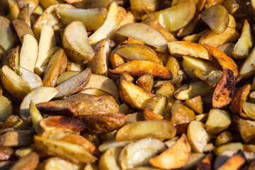 Roast potatoes in a large pan. Delicious food at the festival. Many potatoes on the table in a metal tray.