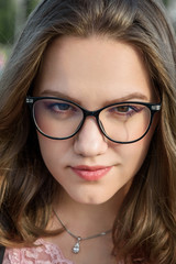 Obraz premium Portrait of brunette girlwith glasses. Girl in black jacket with long hair on the street. Plus size model