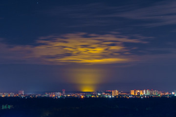 Night city landscape. Glowing cloud in the night sky. Glow in the night sky