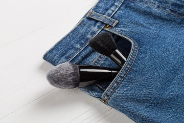 Large makeup brushes in a pocket of blue jeans. Concept, commercial work of a makeup artist, for printing business cards and brochures.