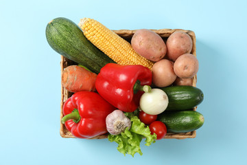 Wicker basket with vegetables on blue background, copy space