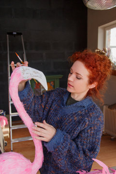 Woman decorating head of flamingo
